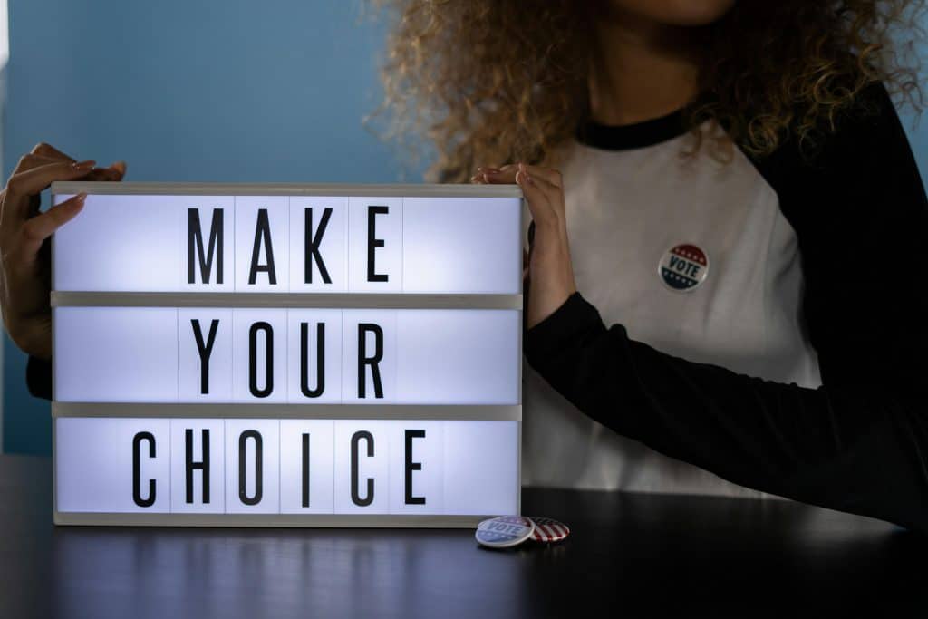 pexels-photo-4669113-4669113 Woman holding lightbox with 'Make Your Choice' promoting civic duty and voting.