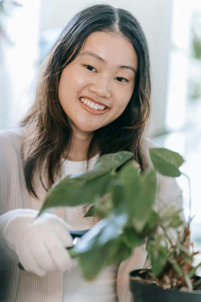 pexels-photo-9413729-9413729 Smiling woman tending to houseplant indoors, showcasing joy in gardening.