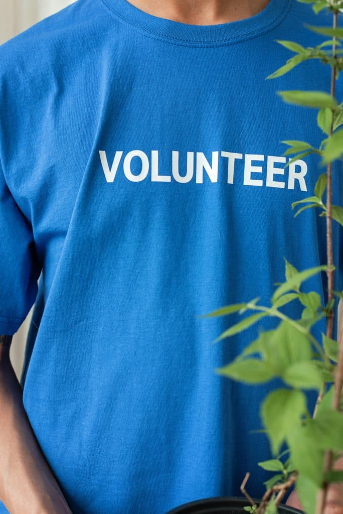 pexels-photo-8543010-8543010 Blue-shirted volunteer with plant, reflecting community work and environmental care.